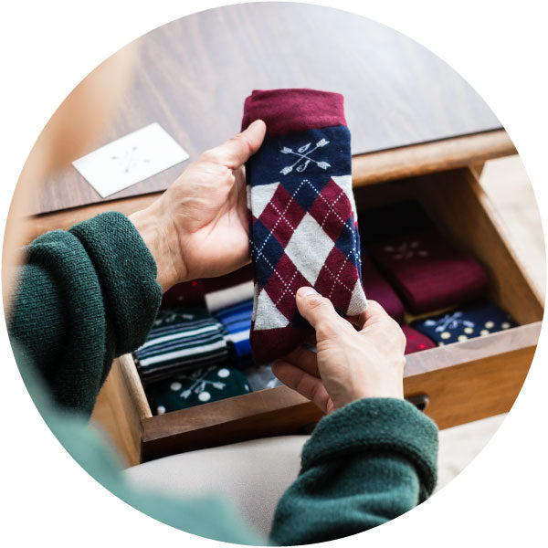 a man holding up a pair of argyle dress socks taken out of a sock drawer