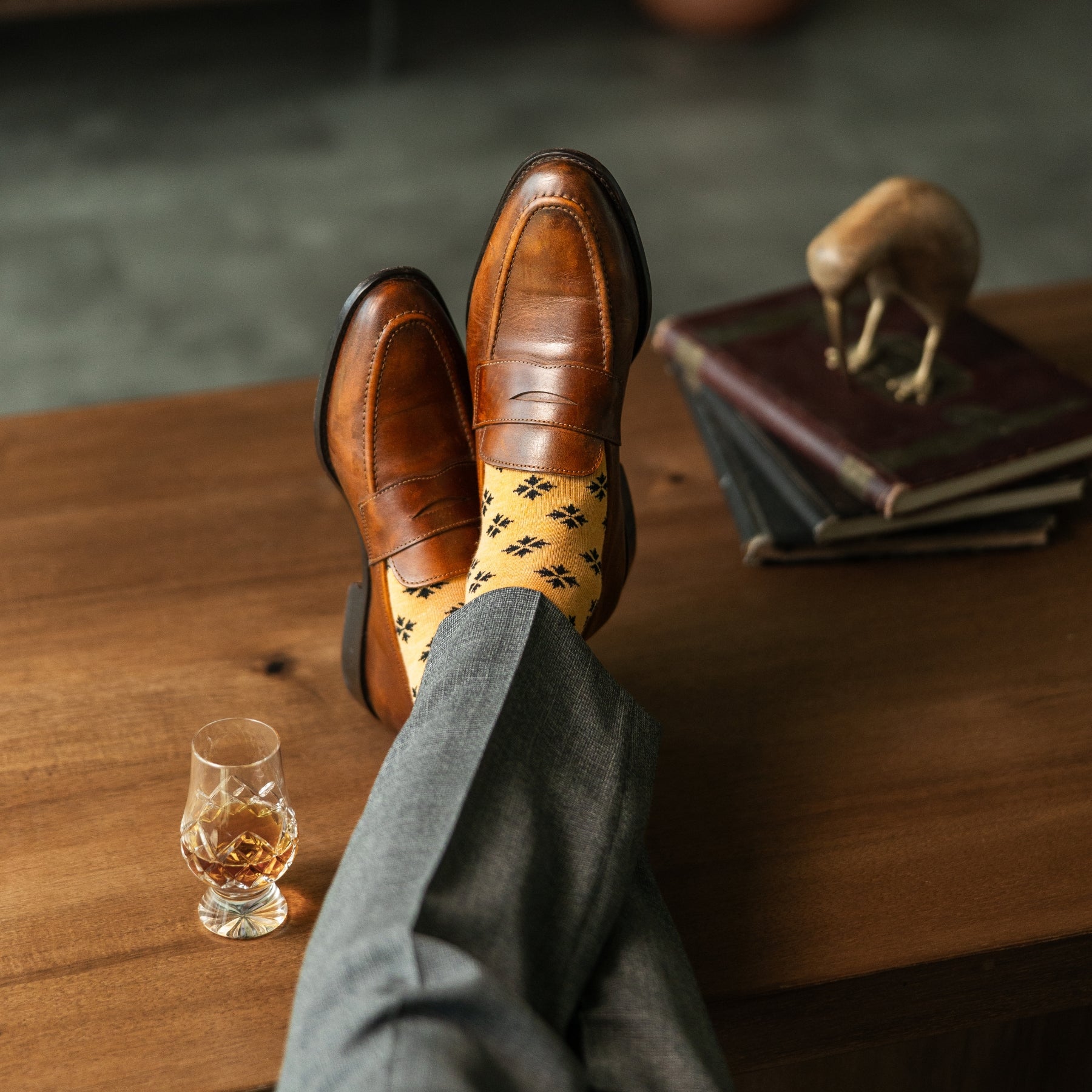 A light rust-orange men's dress sock with a bold black leaf motif