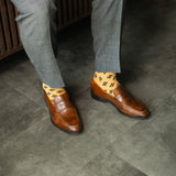 A light rust-orange men's dress sock with a bold black leaf motif