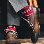 a men's dress sock with varying hues of red, with white and black contrasting stripes