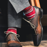 a men's dress sock with varying hues of red, with white and black contrasting stripes