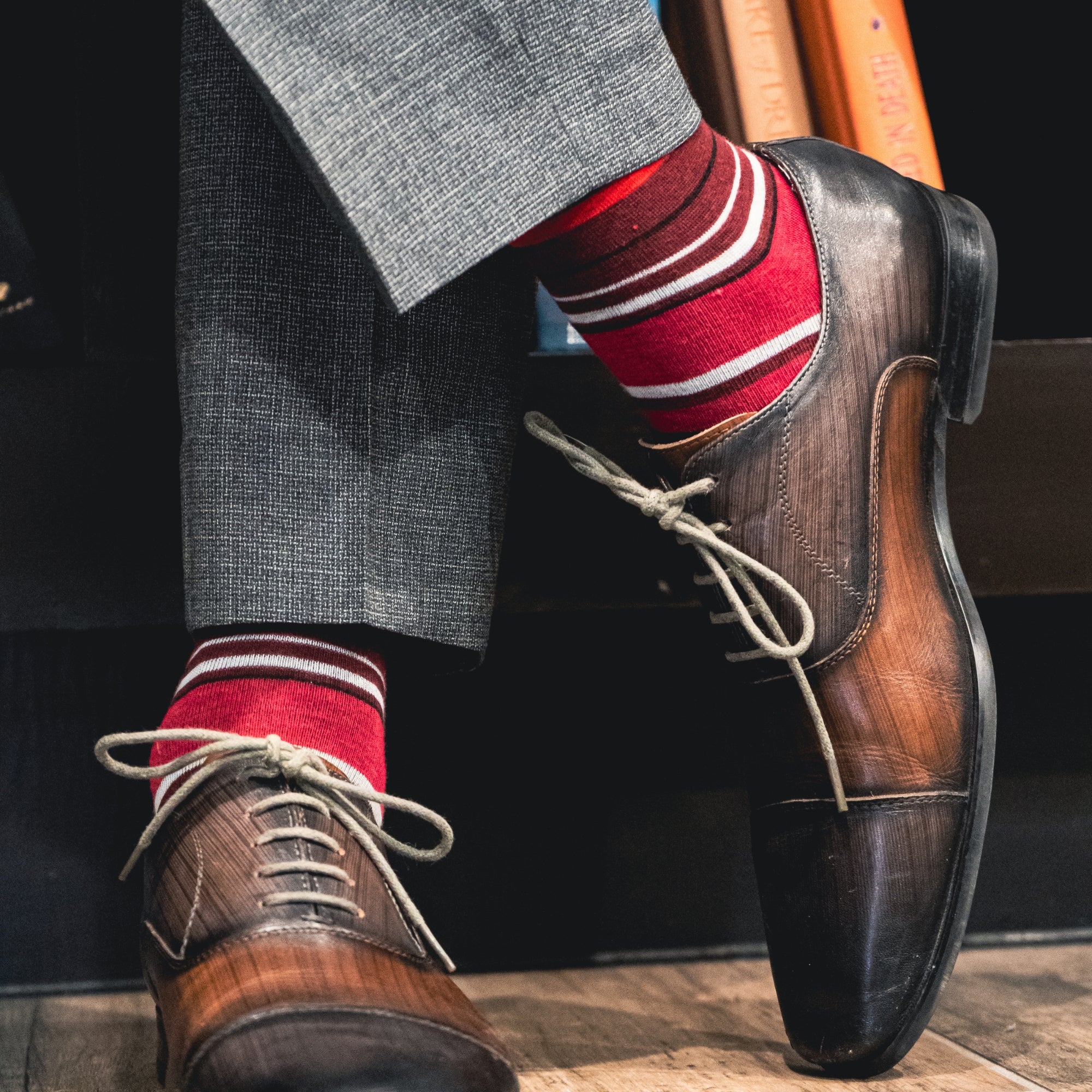 a men's dress sock with varying hues of red, with white and black contrasting stripes