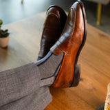 A grey men's dress sock with a navy blue vertical stripe pattern