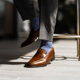 Man wearing heathered blue men's dress sock with ocean blue micro squares with grey slacks and brown shoes