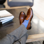 Man wearing heathered blue men's dress sock with ocean blue micro squares with grey slacks and brown shoes