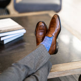 Man wearing heathered blue men's dress sock with ocean blue micro squares with grey slacks and brown shoes