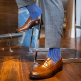 Man wearing solid, blue, and navy blue ribbed men's dress socks and brown shoes.