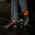 Man wearing orange, solid, tangerine ribbed men's dress socks.