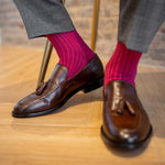 Man sitting wearing ruby, solid, magenta ribbed men's dress socks.