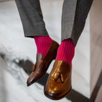 Man sitting wearing ruby, solid, magenta ribbed men's dress socks.