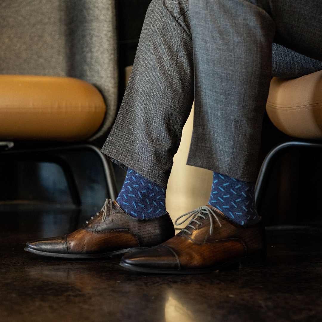 A dark blue men's dress sock with a light blue sprinkle pattern