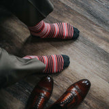 Man wearing coral, grey and white striped socks and dress shoes