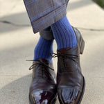 Man wearing solid, blue, and navy blue ribbed men's dress socks and shoes.