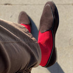 Man sitting with legs crossed wearing rose red ribbed men's dress socks.