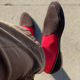 Man sitting with legs crossed wearing rose red ribbed men's dress socks.