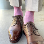 Man wearing light grey slacks, pink socks, and brown shoes.