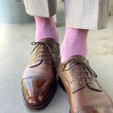 Man wearing light grey slacks, pink socks, and brown shoes.