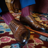 Man wearing Deep red sock with light blue pin dots, brown shoes, and blue trousers