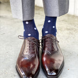 Man wearing grey pants, navy blue socks with white polka dots, and brown dress shoes.