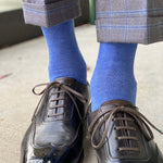 Man standing wearing steel blue men's dress socks, and black shoes.