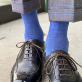 Man standing wearing steel blue men's dress socks, and black shoes.