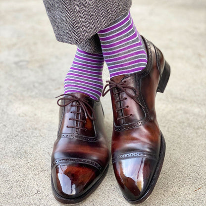 A man wearing purple, grey, and white striped dress socks and brown dress shoes