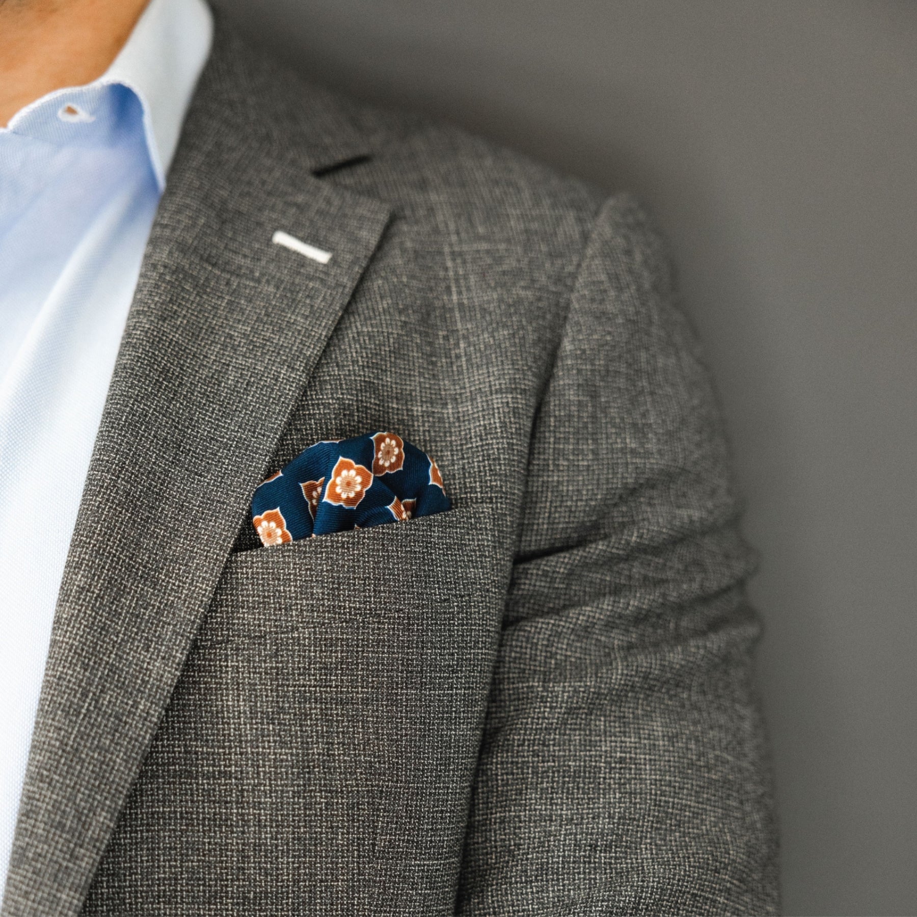 man wearing brown and blue floral pocket square with grey suit jacket and blue dress shirt