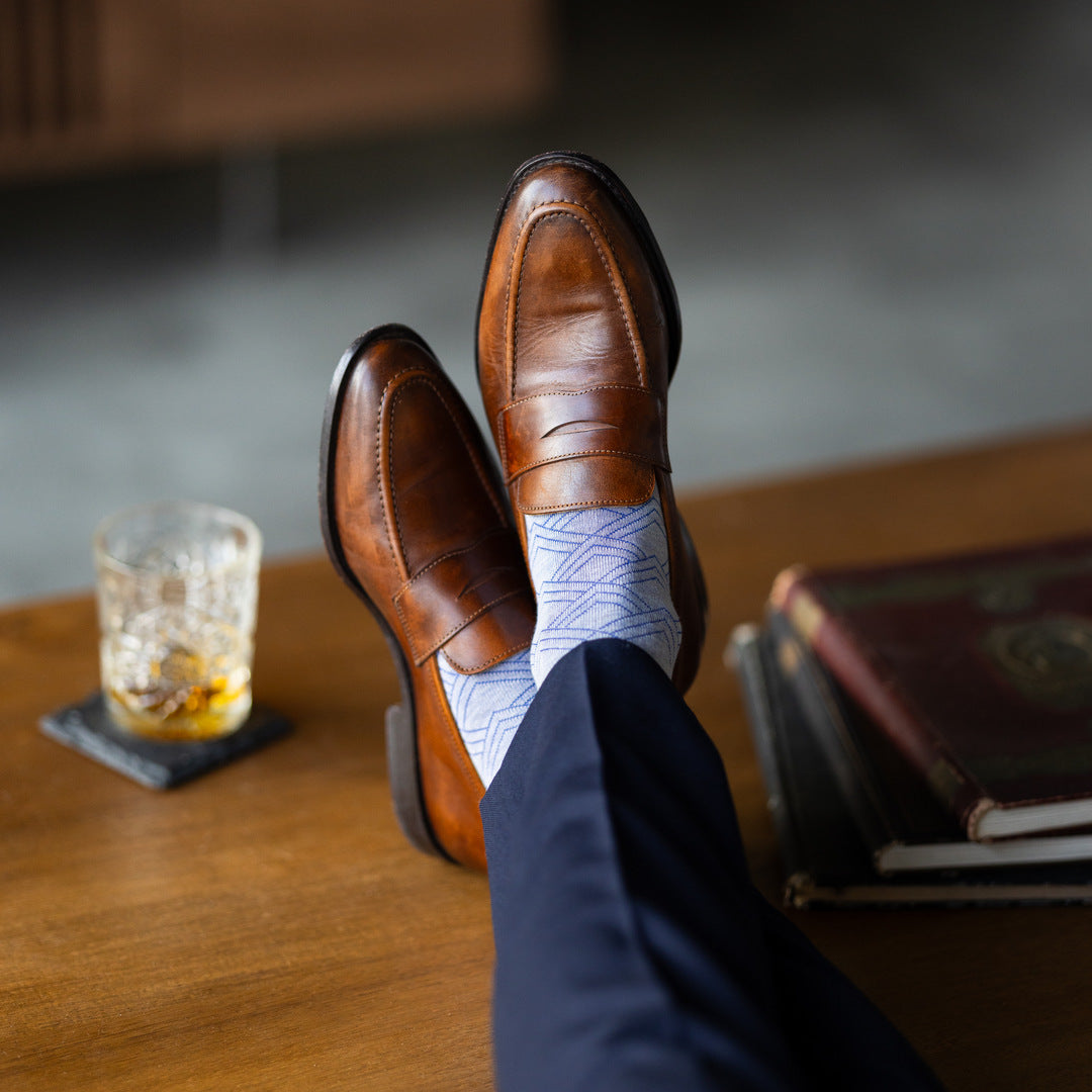 The Blue-Grey & Cobalt Square-Grid dress socks with tailored trousers and loafers in a seated lounge view