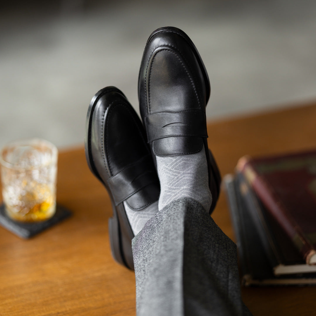 The Pearl Grey Square-Grid dress socks with tailored trousers and loafers in a seated lounge view