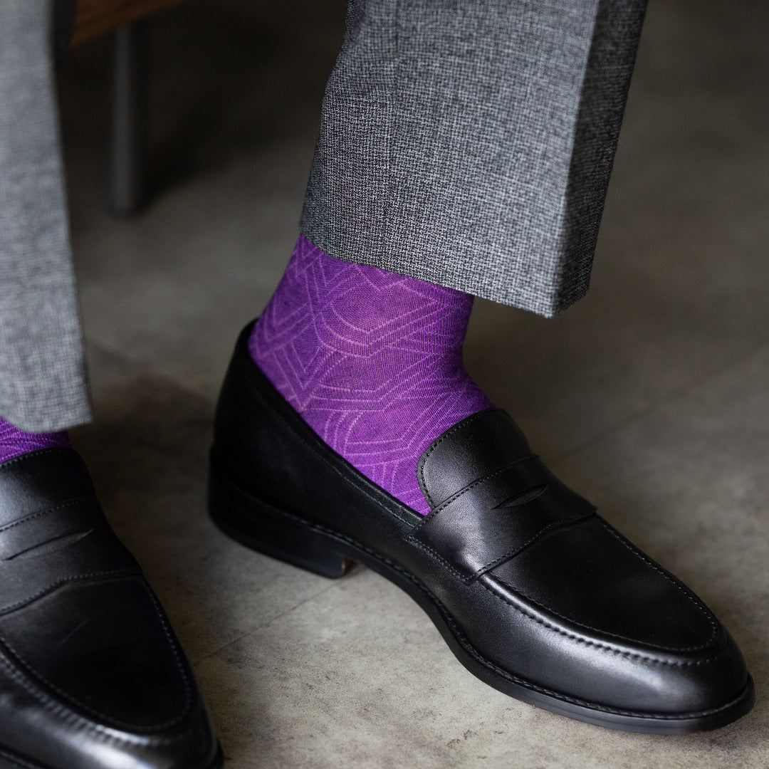 The Plum & Lavender Square-Grid dress socks with tailored trousers and loafers in a seated lounge view
