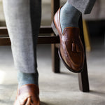 The Sage Green & Taupe Square-Grid dress sock with a loafer in a raised-foot close-up