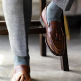The Sage Green & Taupe Square-Grid dress sock with a loafer in a raised-foot close-up