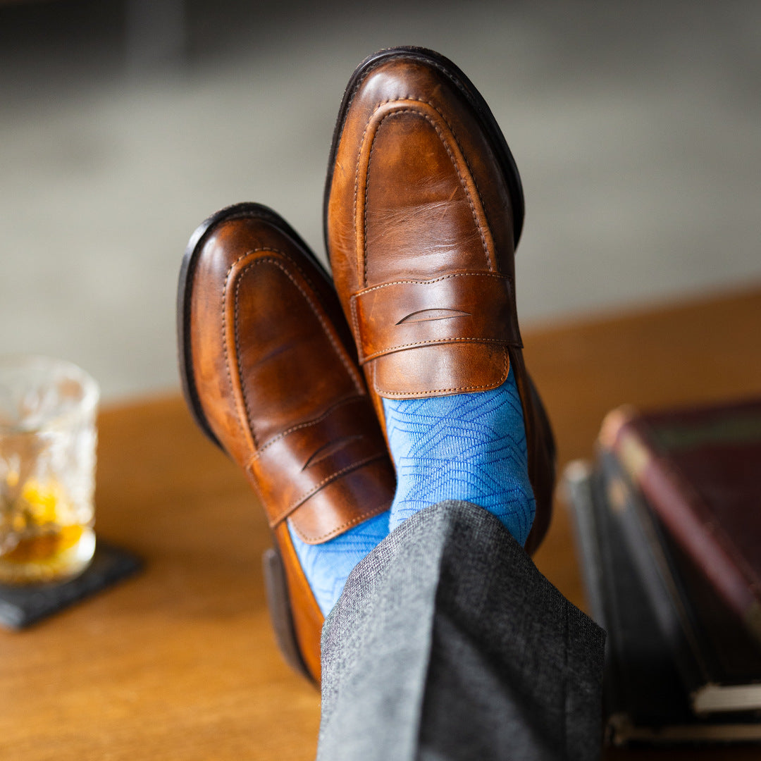 The Azure Blue & Cobalt Square-Grid dress socks with tailored trousers and loafers in a lounge feet-up view