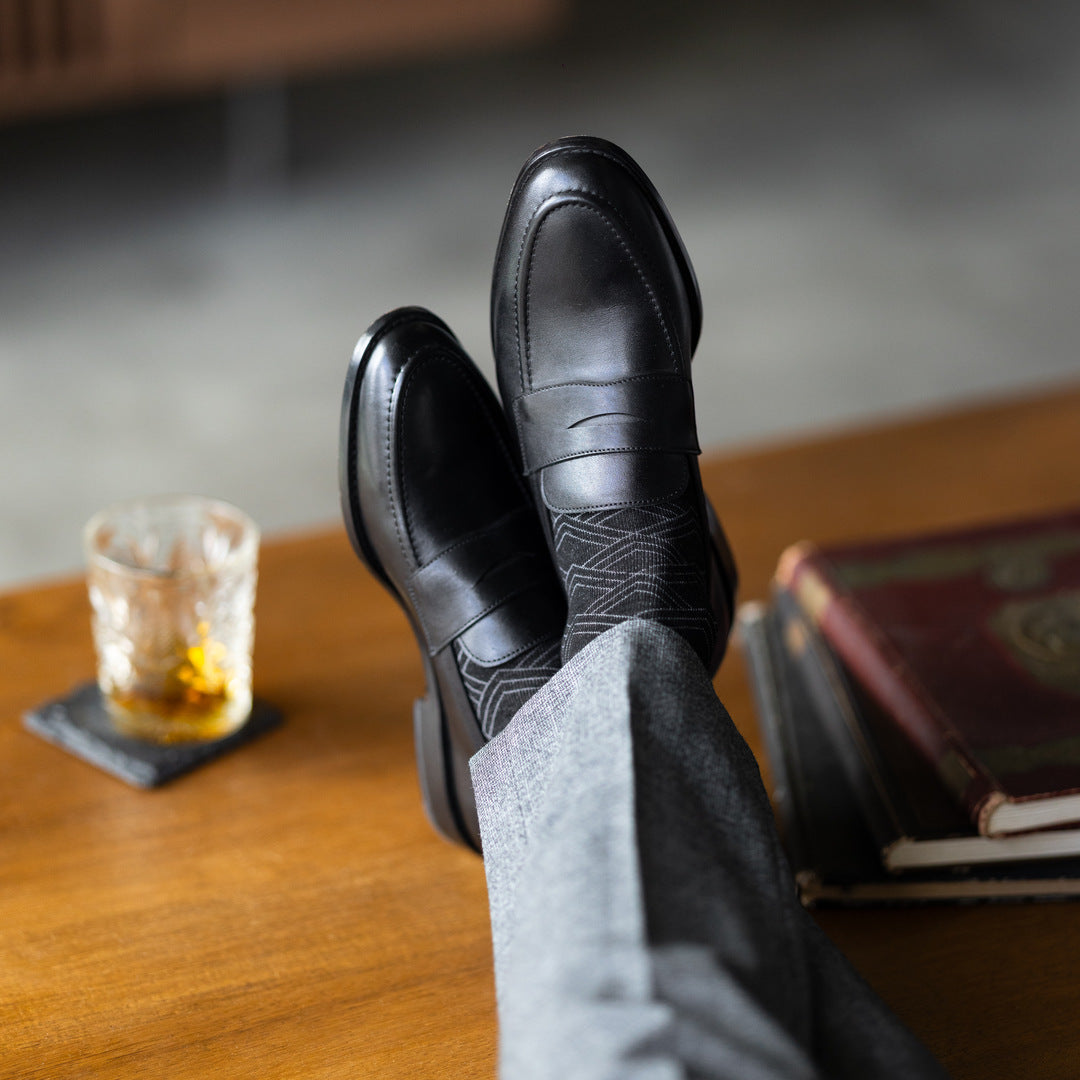 The Black & Silver Square-Grid dress socks with tailored trousers and loafers in a lounge feet-up view