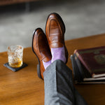 The Lavender & Plum Square-Grid dress socks with tailored trousers and loafers in a lounge feet-up view