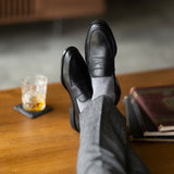 The Pearl Grey Square-Grid dress socks with tailored trousers and loafers in a lounge feet-up view