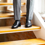 The Sage Green & Taupe Square-Grid dress socks with grey trousers and black dress shoes on warm loft stairs