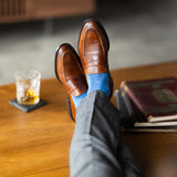 The Azure Blue & Cobalt Square-Grid dress socks with tailored trousers and loafers in a seated lounge view