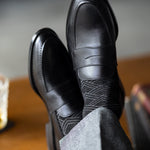 The Black & Silver Square-Grid dress socks with tailored trousers and loafers in a seated lounge view