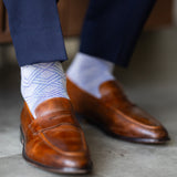 The Blue-Grey & Cobalt Square-Grid dress socks with tailored trousers and loafers in a seated lounge view