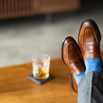 The Azure Blue & Cobalt Square-Grid dress sock with a loafer in a raised-foot close-up