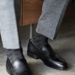 The Black & Silver Square-Grid dress sock with a loafer in a raised-foot close-up