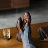 The Sage Green & Taupe Square-Grid dress sock with a loafer in a raised-foot close-up