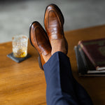 The Blue-Grey & Cobalt Square-Grid dress sock with tailored trousers and a loafer in a seated foreground view