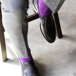 The Plum & Lavender Square-Grid dress sock with tailored trousers and a loafer in a seated foreground view