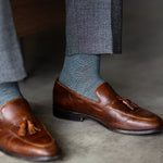 The Sage Green & Taupe Square-Grid dress sock with a loafer in a raised-foot close-up