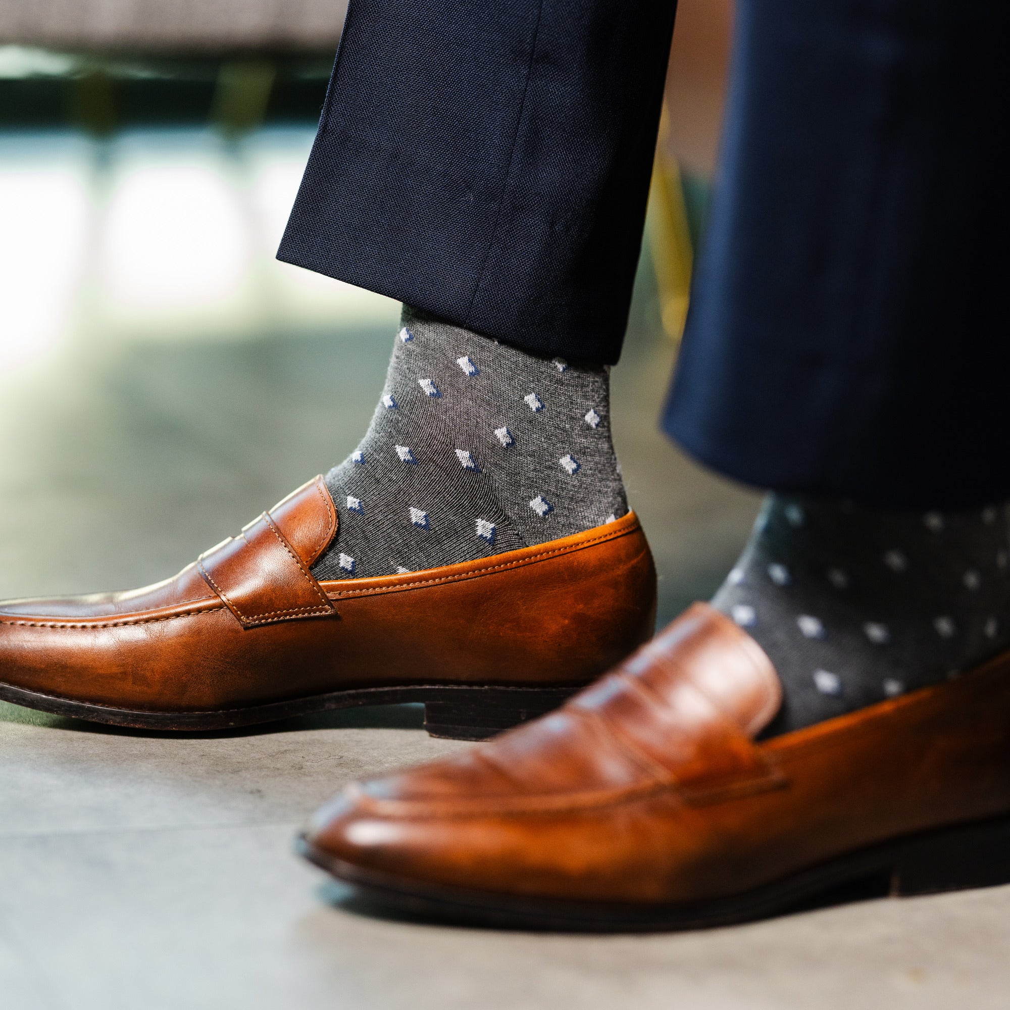 Close-up of grey Gemstones dress socks with navy trousers and brown loafers