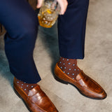 Brown Gemstones dress socks with navy trousers and brown penny loafers while seated