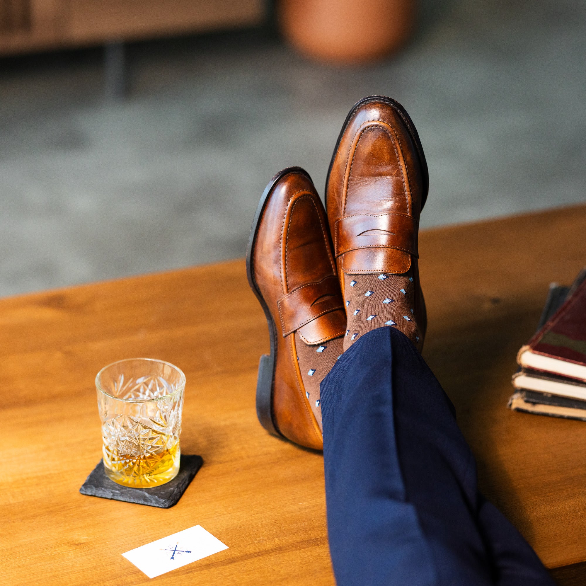 Close-up of brown Gemstones dress socks with navy trousers and penny loafers