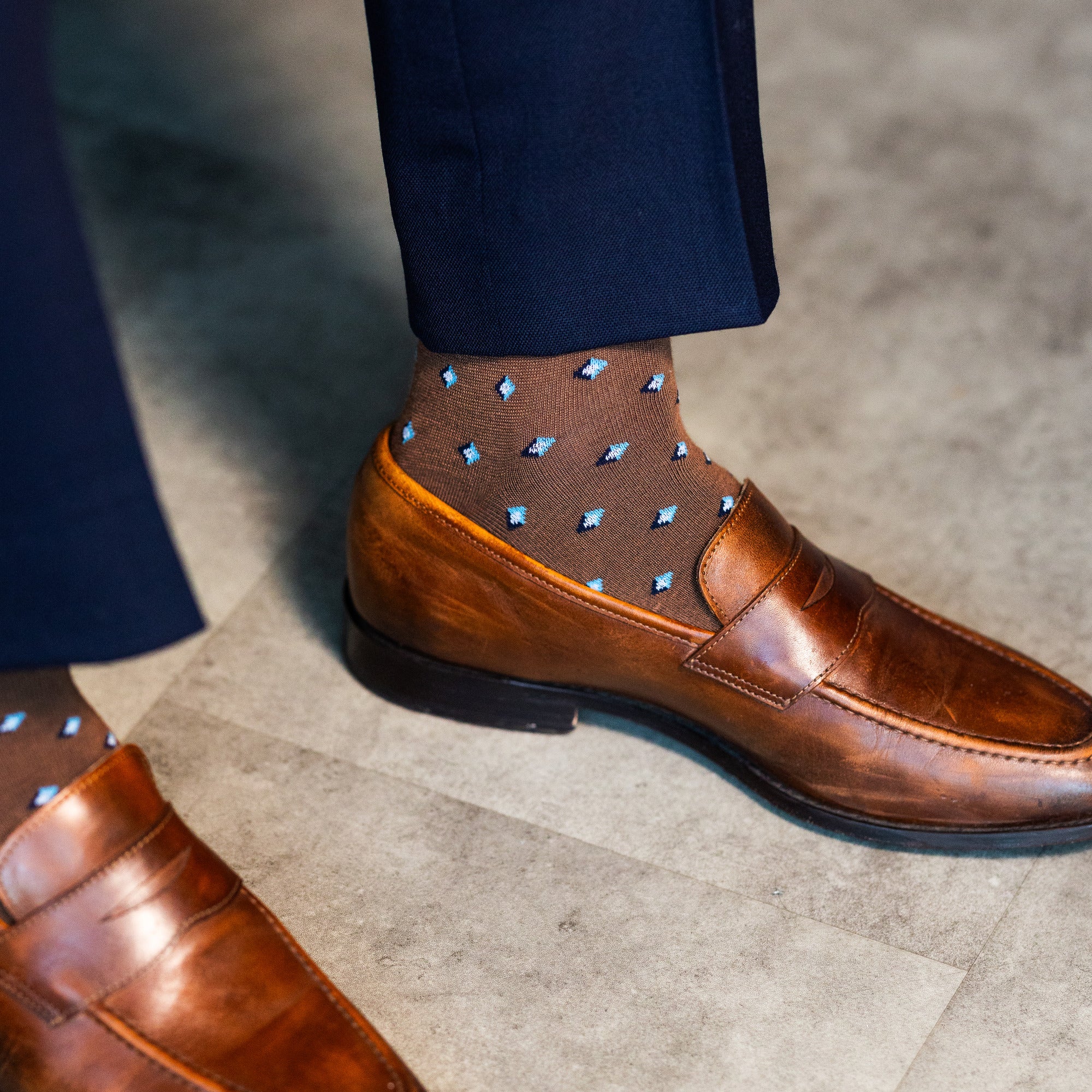 Close-up of a brown Gemstones dress sock with navy trousers and a brown loafer